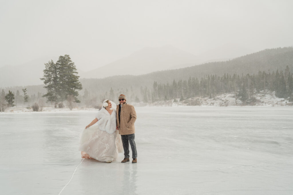 A couple stands on a frozen lake in Rocky Mountain National Parl