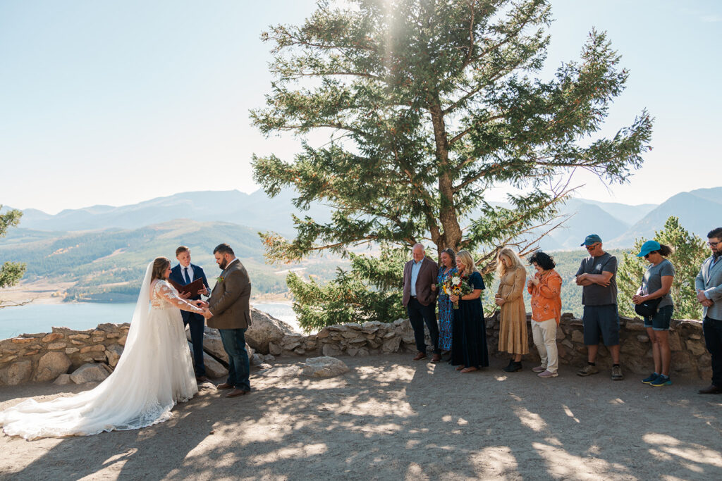 A couple stands hand in hand during a wedding ceremony at Sapphire Point Overlook in Breckenridge Colorado